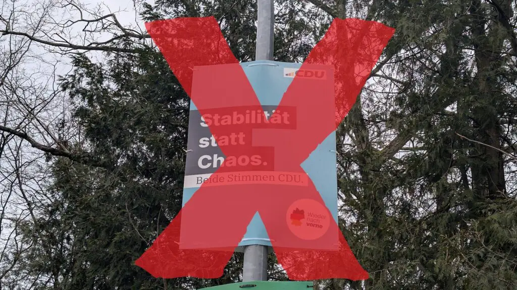 Auf einem politischen Plakat an einem Laternenpfahl steht "Stabilität statt Chaos. Beide Stimmen CDU", teilweise verdeckt durch ein großes rotes X. Im Hintergrund sind Bäume mit kahlen Ästen zu sehen.
