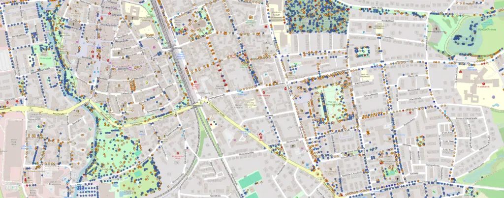 Ein detaillierter Stadtplan mit eingezeichneten Straßen, Parks und Gebäuden. Zahlreiche farbige Punkte und Symbole sind über die Karte verstreut und weisen auf verschiedene Orte oder interessante Punkte in einem Stadtviertel hin.