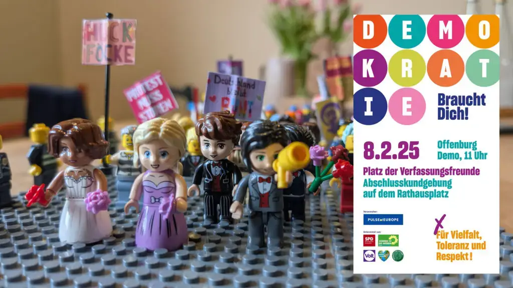 Eine Gruppe von LEGO Minifiguren in formeller Kleidung hält Protestschilder, daneben ein buntes Plakat, das für eine Demokratie-Kundgebung am 8.2.25 in Offenburg wirbt und für Vielfalt, Toleranz und Respekt plädiert.