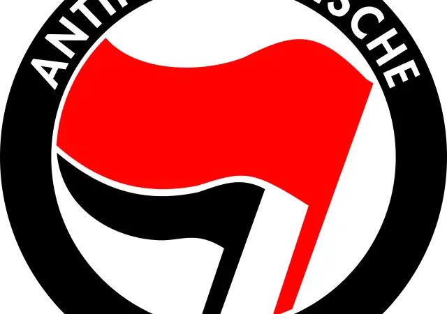 Ein rundes Logo mit dem Schriftzug ANTIFASCHISTISCHE AKTION um zwei wehende Fahnen, eine rote und eine schwarze, auf weißem Hintergrund mit schwarzem Rand.