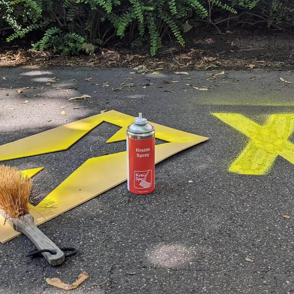 Gelbes Kreuz, Schablone und Kreidespray auf der Straße