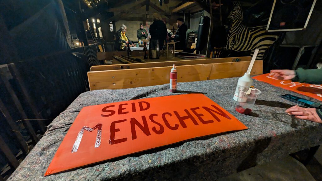 Beim Plakatemalen. Im Vordergrund ein Plakat mit dem Text: Seid Menschen