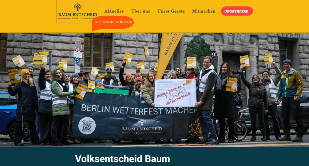 Eine Gruppe von Menschen steht draußen und hält Schilder und Transparente mit der Aufschrift "Berlin wetterfest machen" und unterstützt die Umweltinitiative Baum Entscheid Berlin. Sie scheinen auf einer Straße in der Stadt Wahlkampf zu machen oder eine Kundgebung abzuhalten.