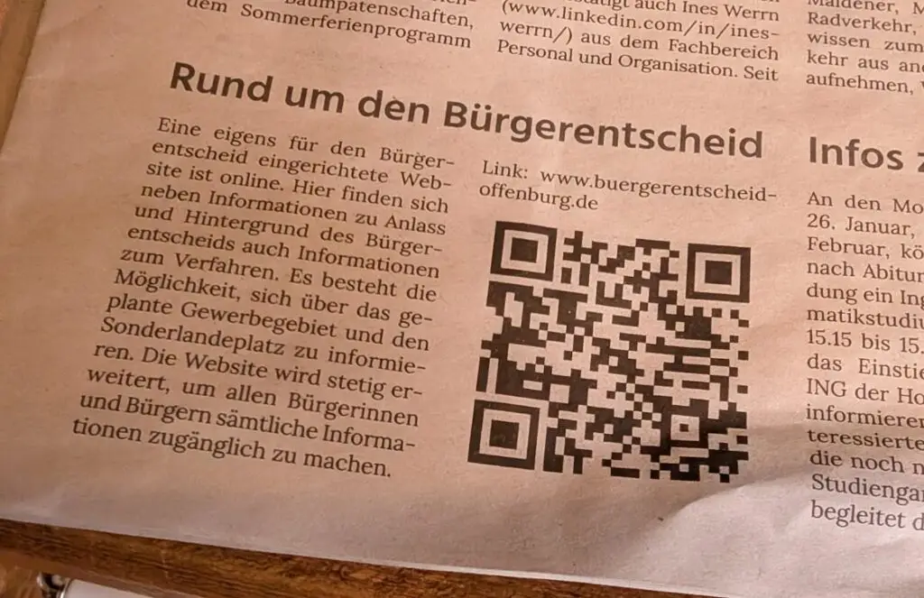Ein Zeitungsartikel über einen Bürgerentscheid mit einem großen QR-Code und einem gedruckten Textabschnitt mit dem Titel Rund um den Bürgerentscheid.