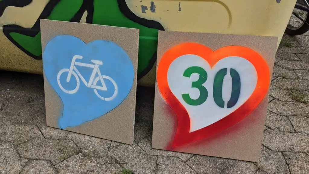 Two concrete tiles with heart motifs: left blue heart with a white bicycle icon; right orange-edged heart with a white center and green '30'
