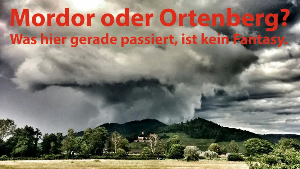 Eine dramatische, dunkle Gewitterwolke schwebt über einer grünen Landschaft um Schloss Ortenberg. Der fettgedruckte rote deutsche Text lautet: Mordor oder Ortenberg? Was hier gerade passiert, ist keine Fantasie.
