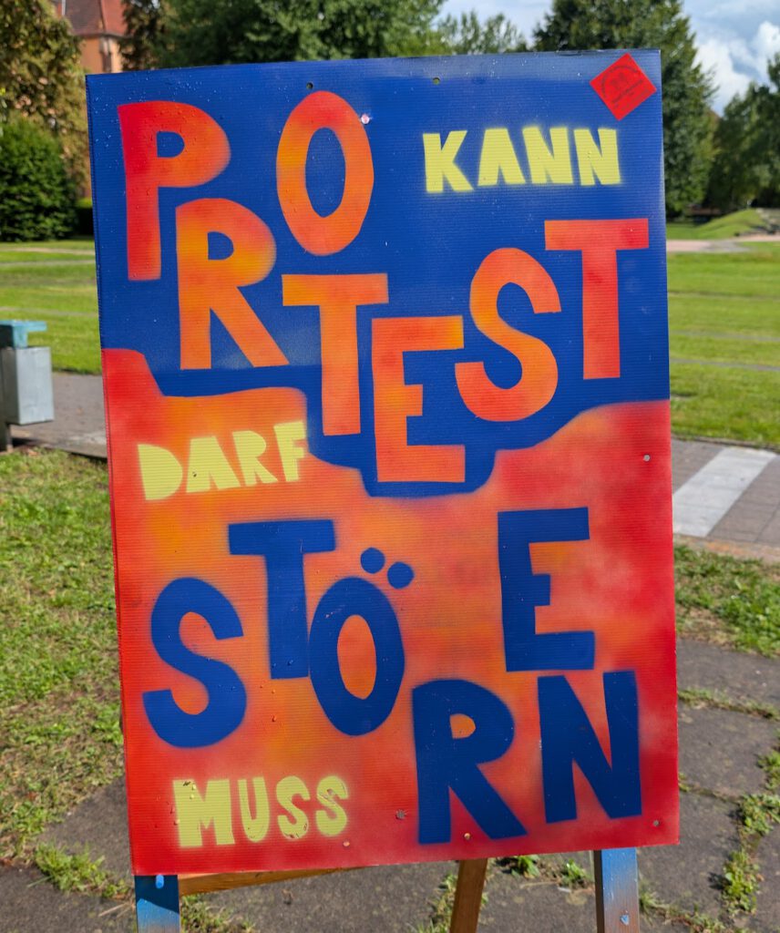 Ein Schild mit dem deutschen Text: Protest kann stören, darf stören, muss stören.
